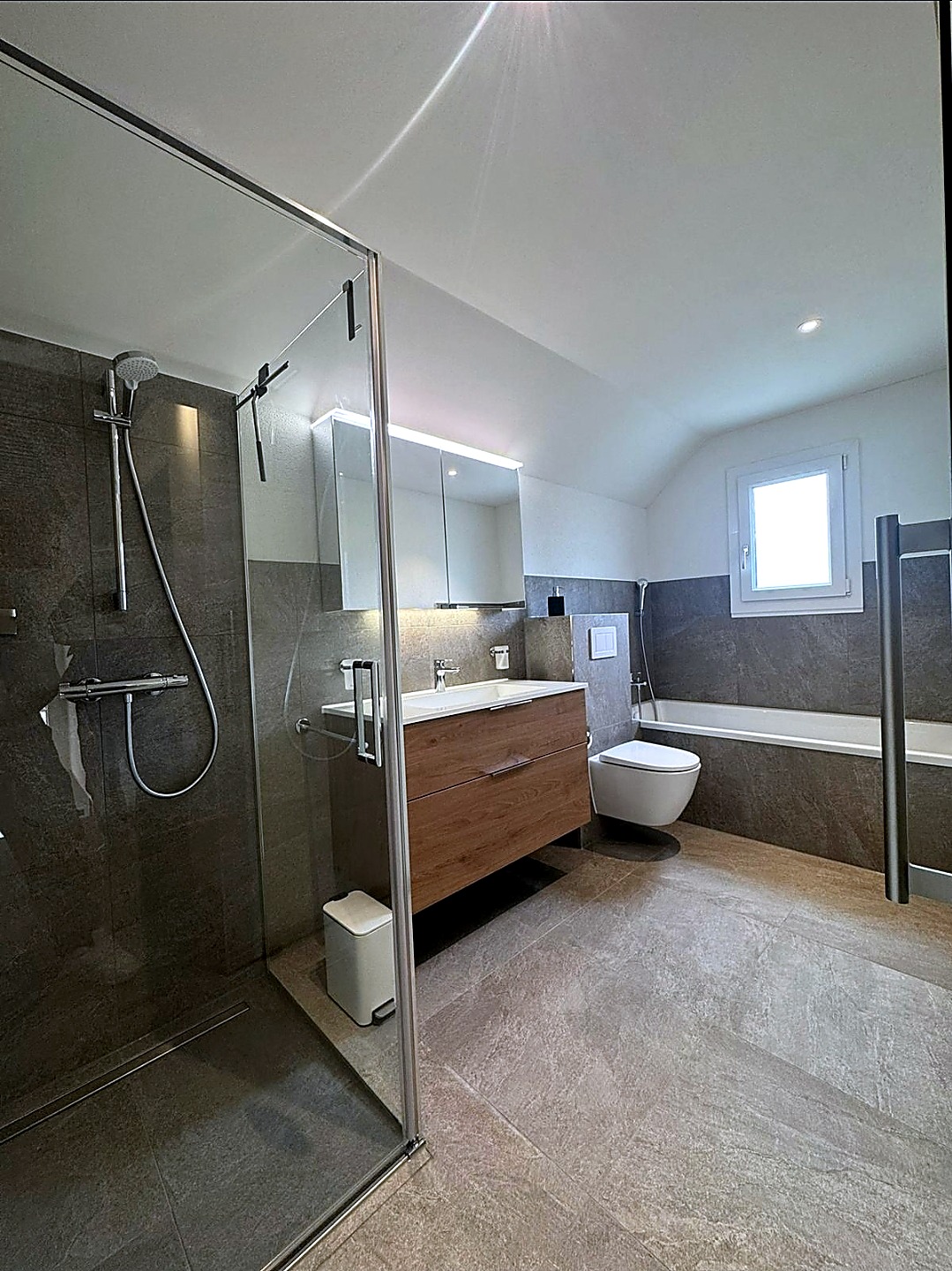 Fertiges Badezimmer mit Glasdusche und Plattenboden